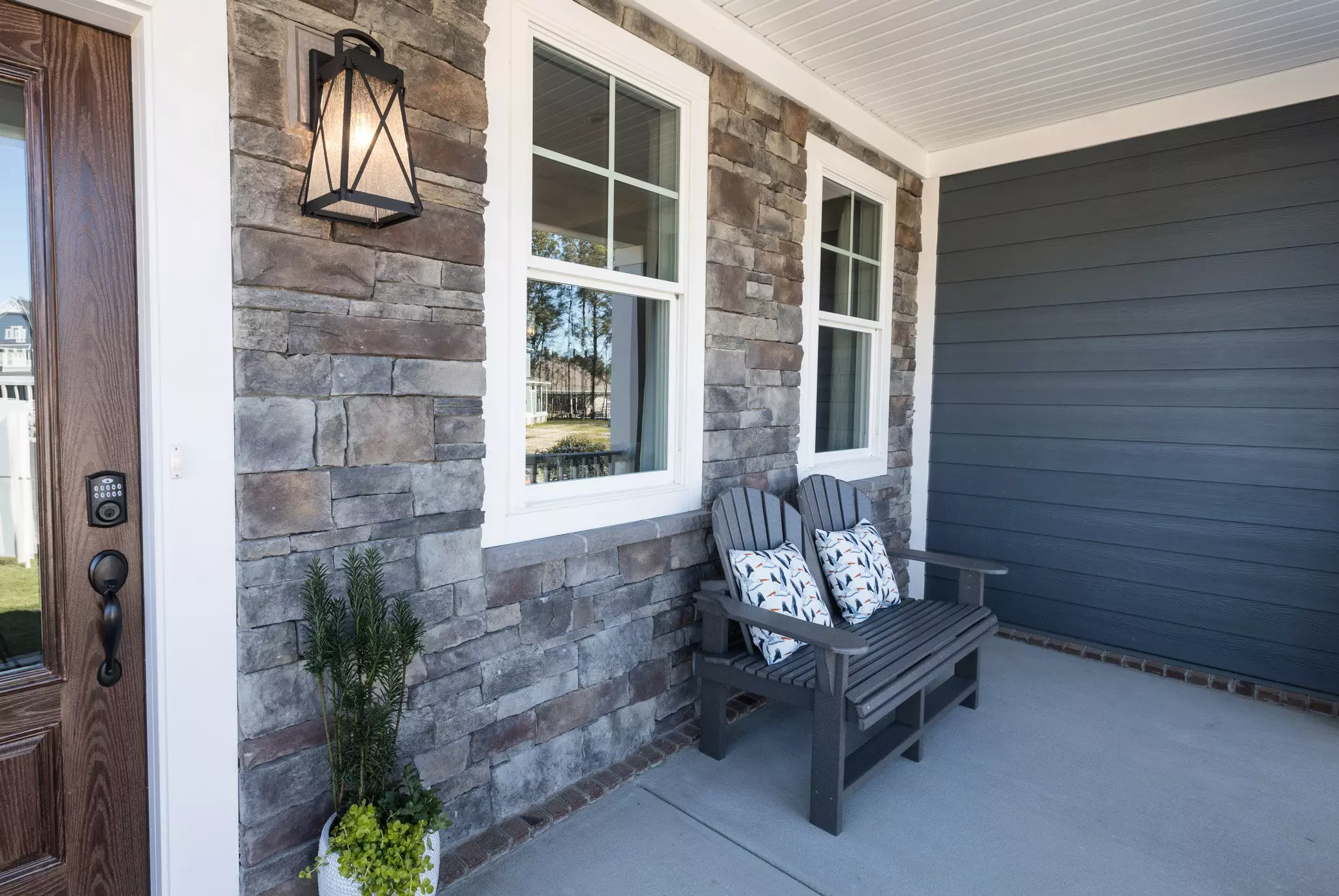Patio bench next to two windows and a front door.