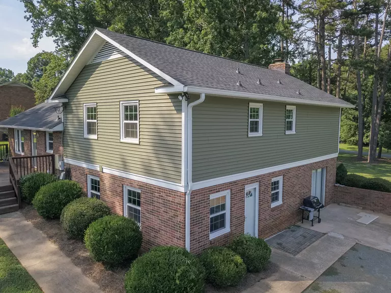 Brick home with green siding and double-hung windows.
