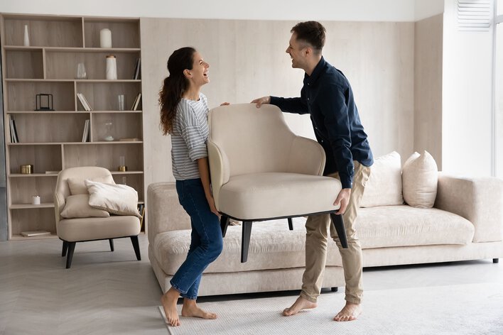 Couple carrying a chair together to prevent sun damage.