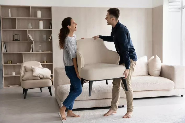 Couple carrying a chair together to prevent sun damage.