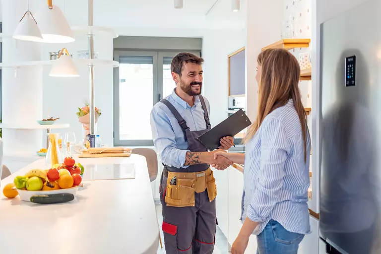 Woman shaking hands with a home improvement contractor in the kitchen of her home.