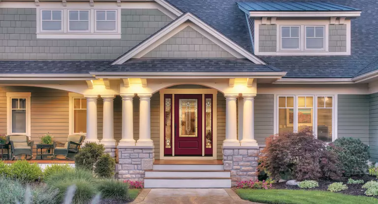 Exterior of a two-story home with a dark red entry door and full sidelites.
