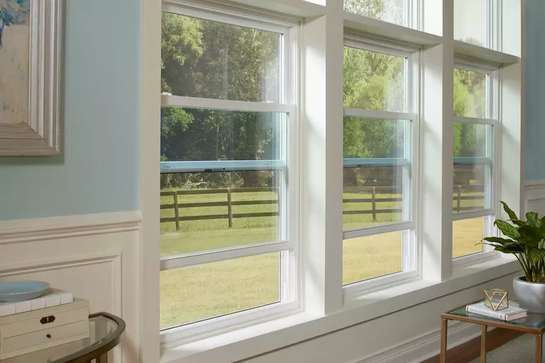 The inside of a home with baby blue walls and three double-hung windows.