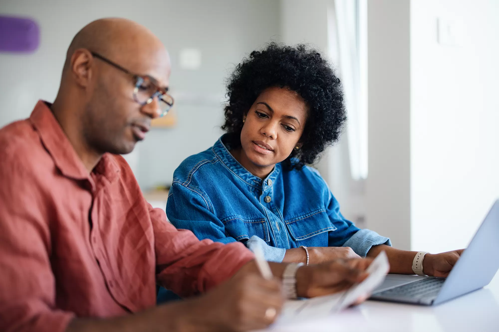 Man and woman reviewing documents in front of a laptop.