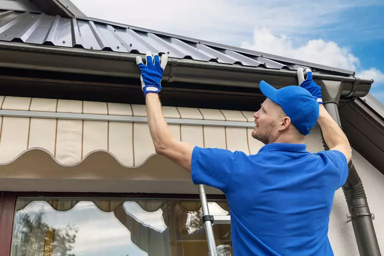 A contractor performing roof and gutter inspections on a Port City home.