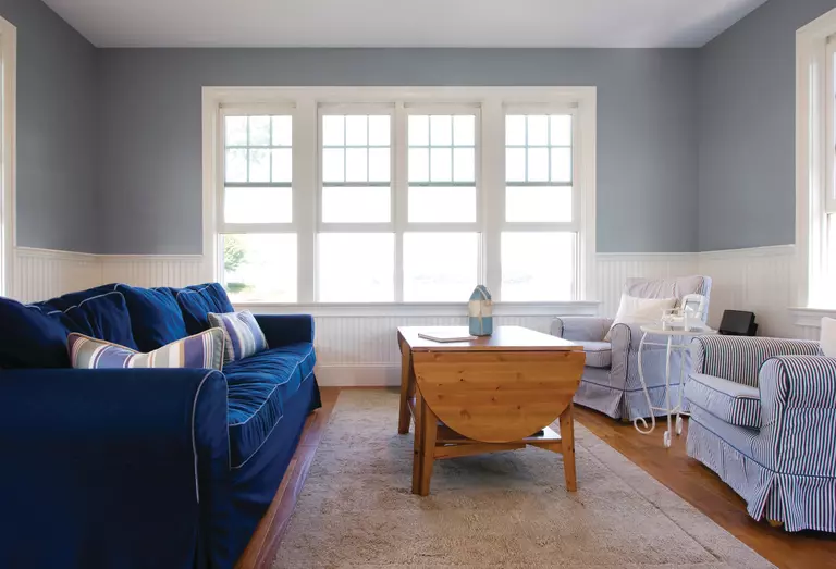 A blue-themed living room with four double-hung windows.