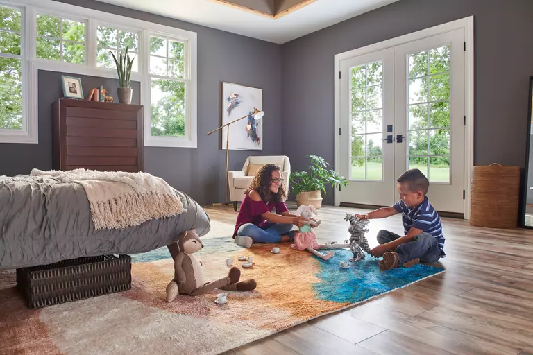 Children playing with toys in a bedroom featuring a pair of exterior doors.