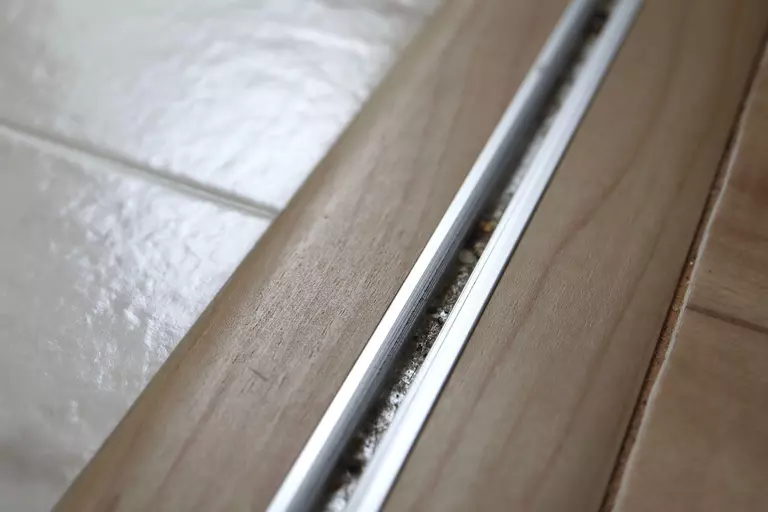 Close-up of a sliding patio door track clogged with debris.