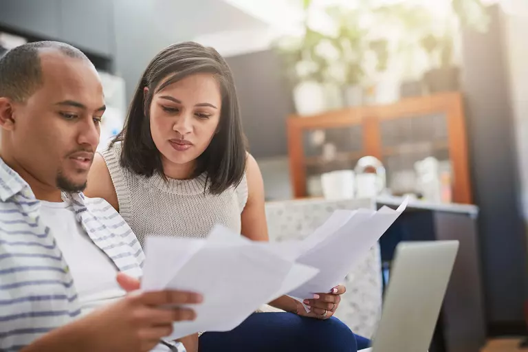 Couple reviewing documents on a sofa.