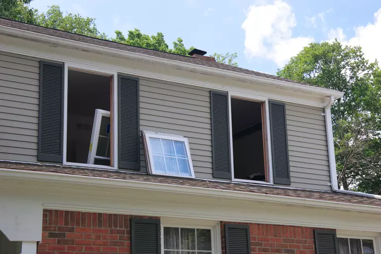 The front of a home with windows being replaced on the second story.