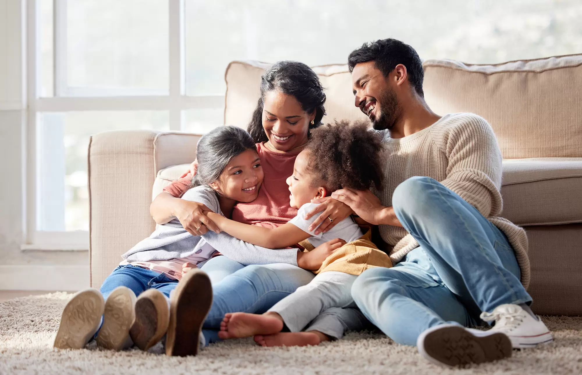 Family of four in front of a living room couch.