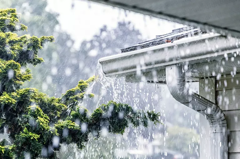 Corner of a gutter overflowing with heavy rain.