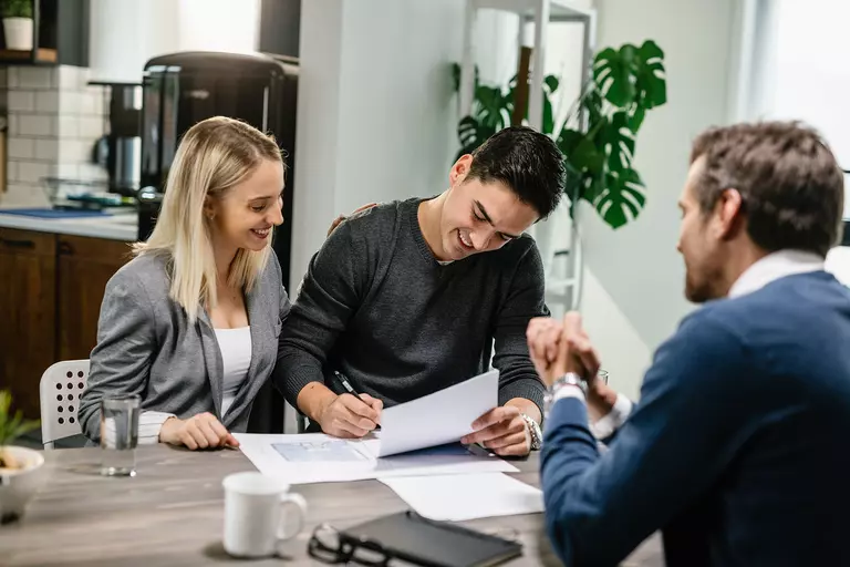 Two men and a woman talking and signing papers.