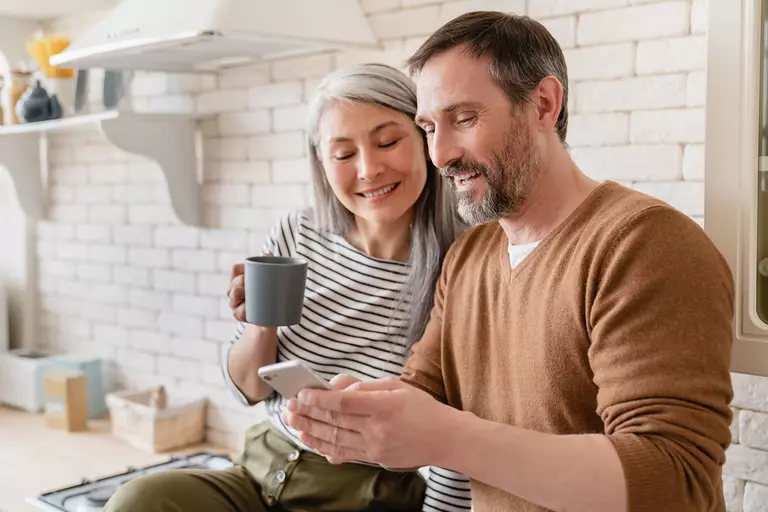 A smiling couple looks at a smartphone together.