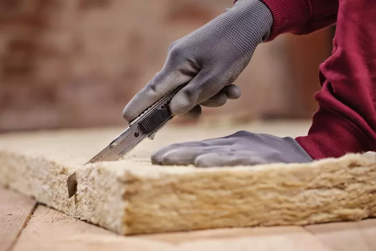 A worker cutting a portion of insulating material.