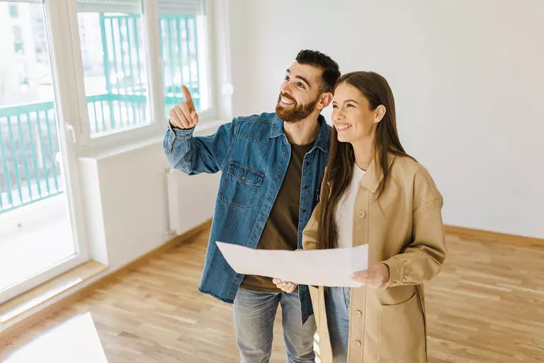 A man and woman smiling together in their home as they decide what home renovations to do for their remodel.