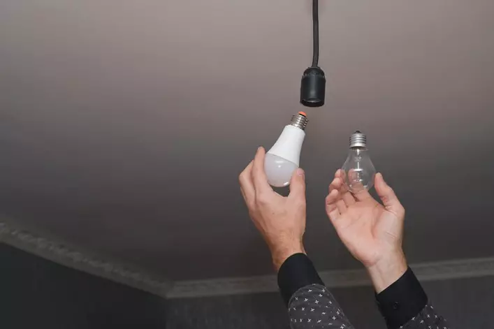 A person changing their old lightbulb to a new ENERGY STAR-certified light bulb