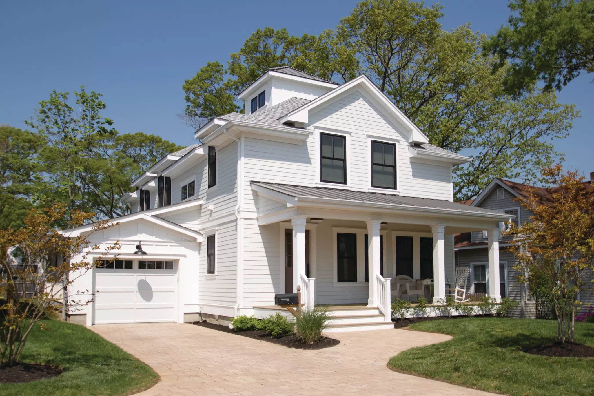 Two-story white farmhouse with multiple window heights and placements.