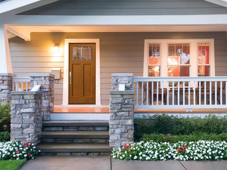 The front of a home with a porch that has stone steps and pillars.