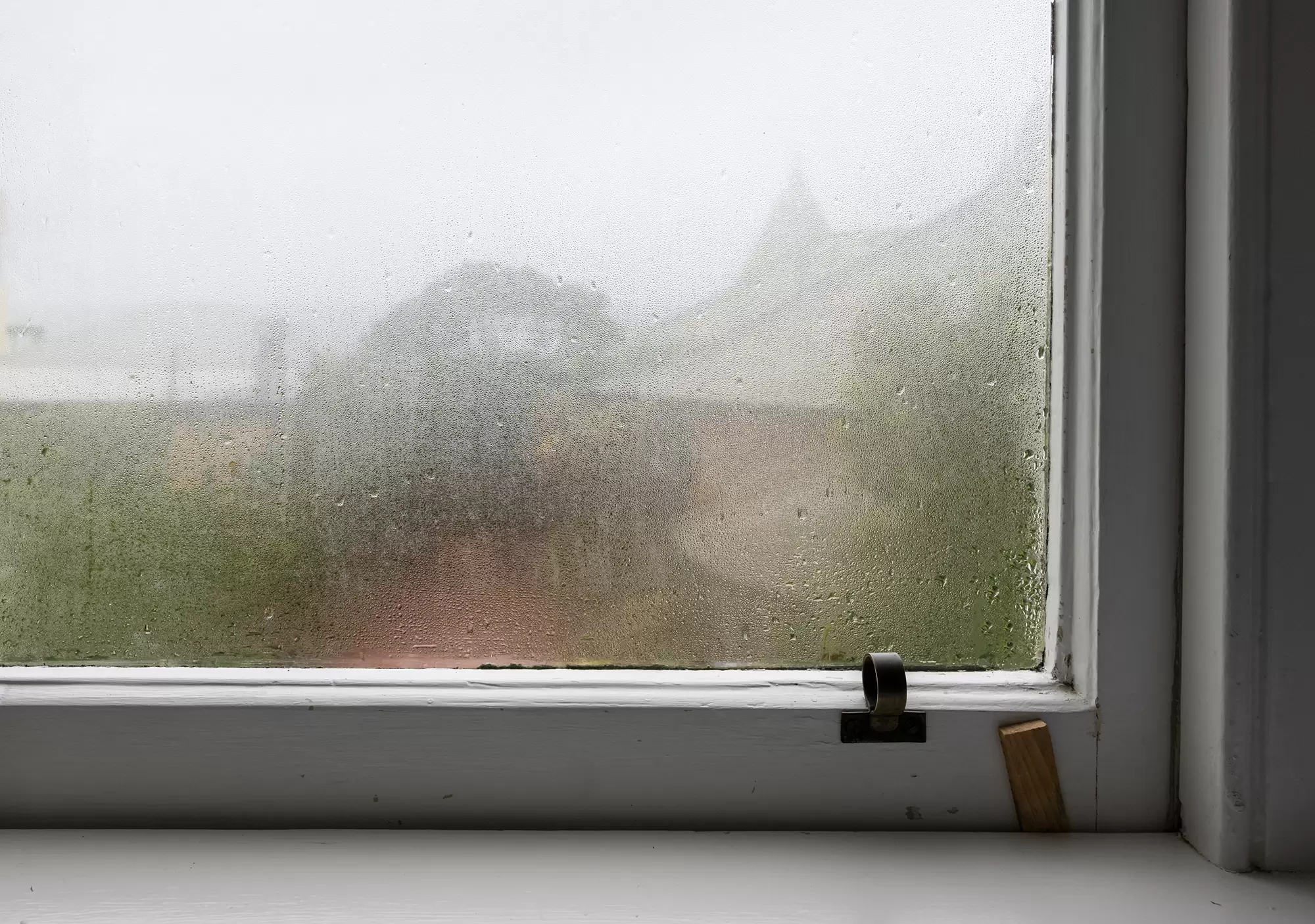 Foggy old window pane with moisture obscuring the outdoor view.
