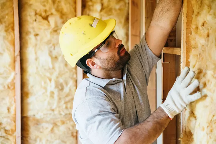 A handyman installs insulation in a home to help prevent condensation on windows.