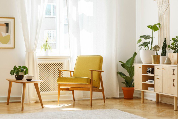 A mid-century modern home with a yellow chair in a room with plants and other modern retro home design features
