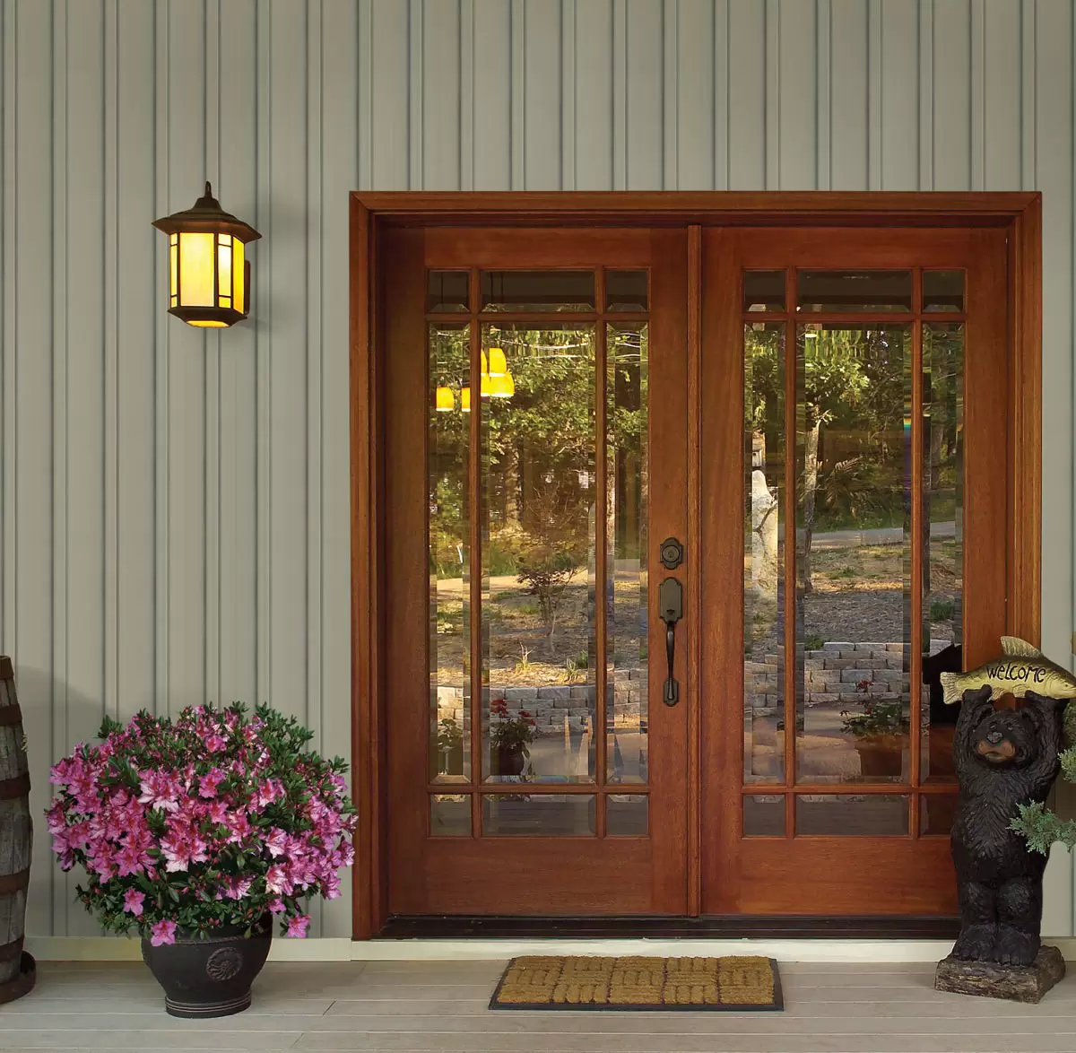 Wooden double doors flanked by decorative elements and vertical siding.