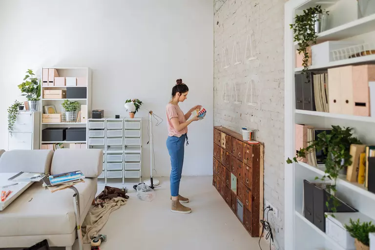 Woman standing in a living area with paint color swatches.