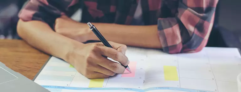 Woman writing notes in a planner.