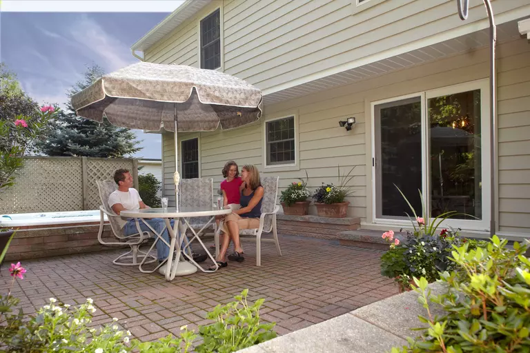 A family seated on a stone patio near a sliding glass door.