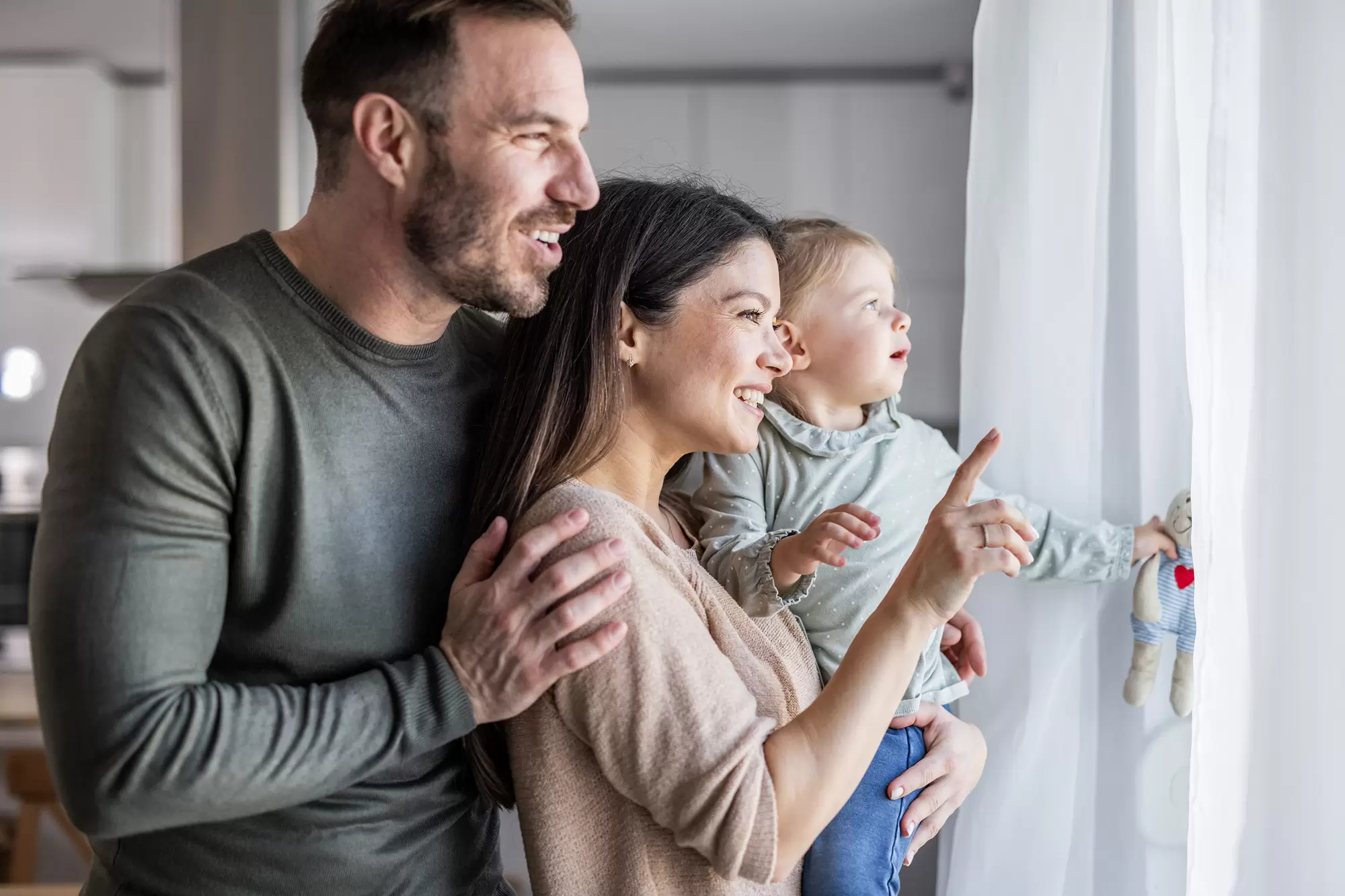Smiling family looking through a window.