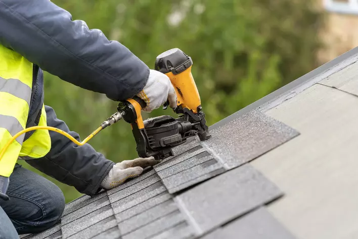 A professional replacing the roof shingles on a home.