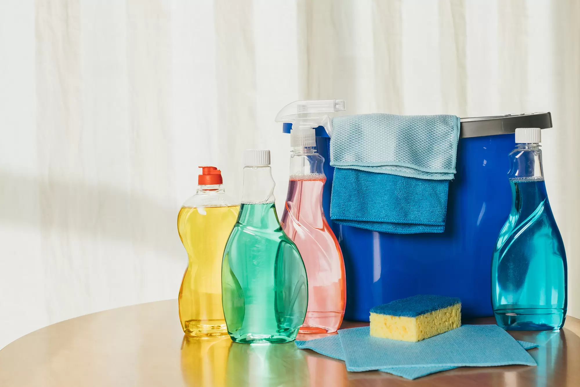 Cleaning supplies with spray bottles and a sponge on a counter.