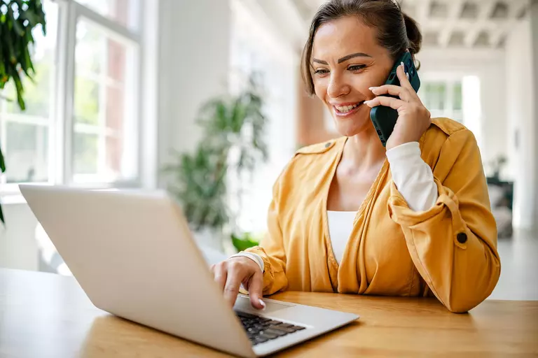 Woman talking on the phone and using a laptop.