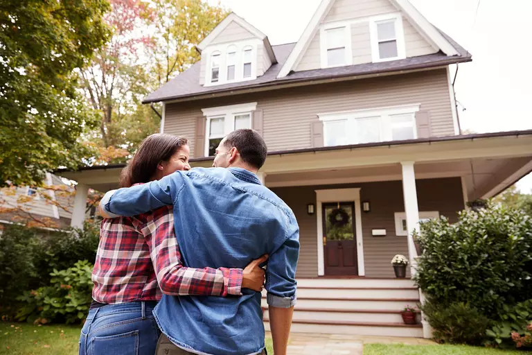 Couple standing outside of their home.