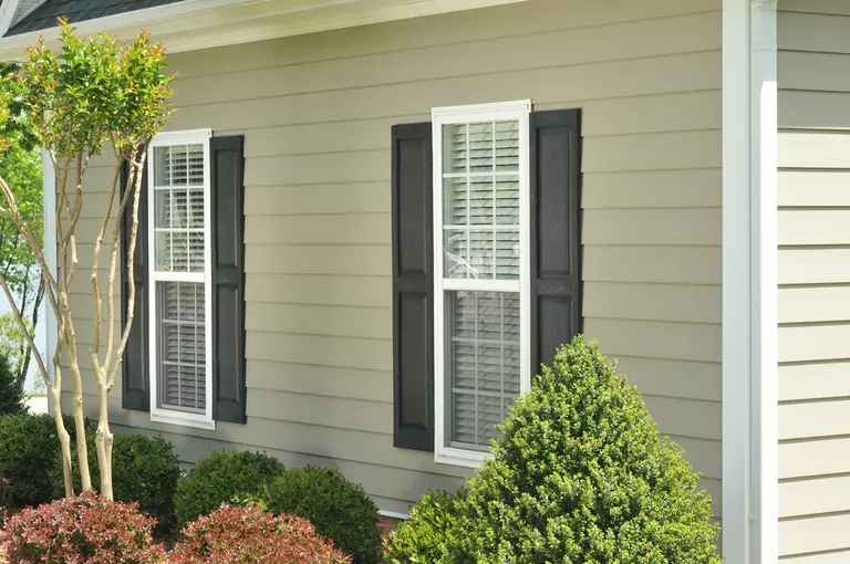 Beige vinyl siding on the front of a Blue Ridge home, with energy-efficient windows that have black shutters to add contrast and pop, boosting curb appeal.
