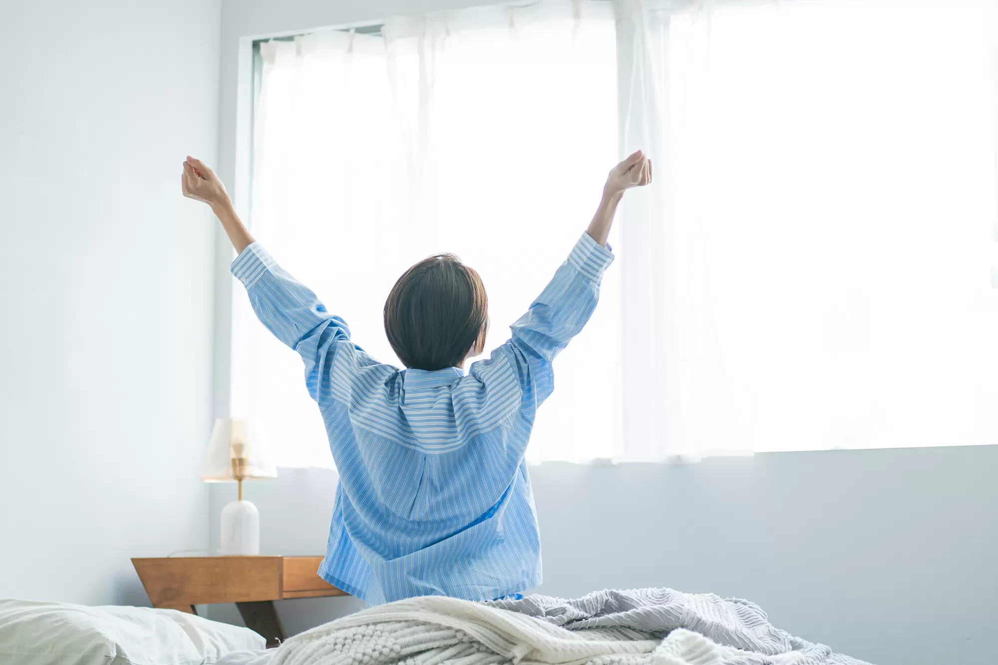 Woman waking up in a sunny bedroom.