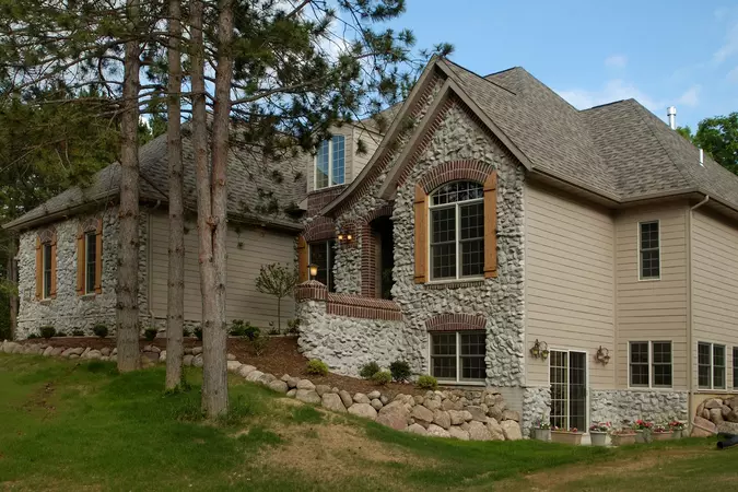 Tan exterior wood-clad double-hung windows on a home with tan and stone siding