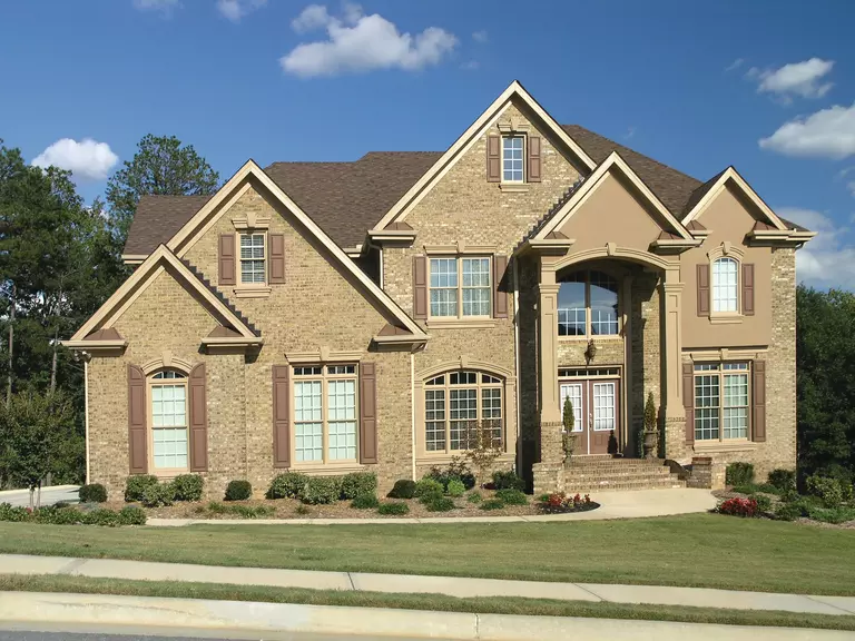 A beige home with a stone exterior using a combination of window configurations.