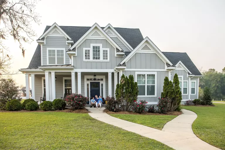 A family in front of their home with new replacement windows and siding.