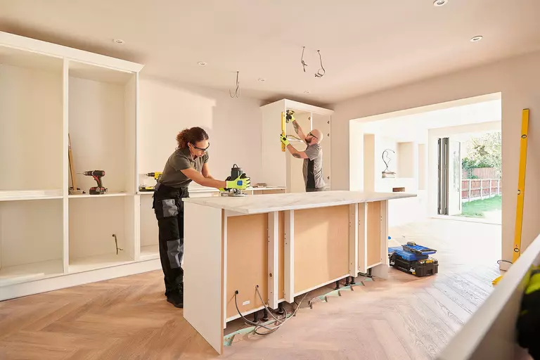 Contractors working on new cabinets and countertops for a kitchen renovation.