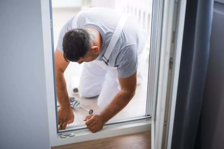 Worker inspecting the bottom of an exterior door frame.