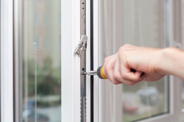A person using a screwdriver to adjust the balances on an old window that won’t stay up.
