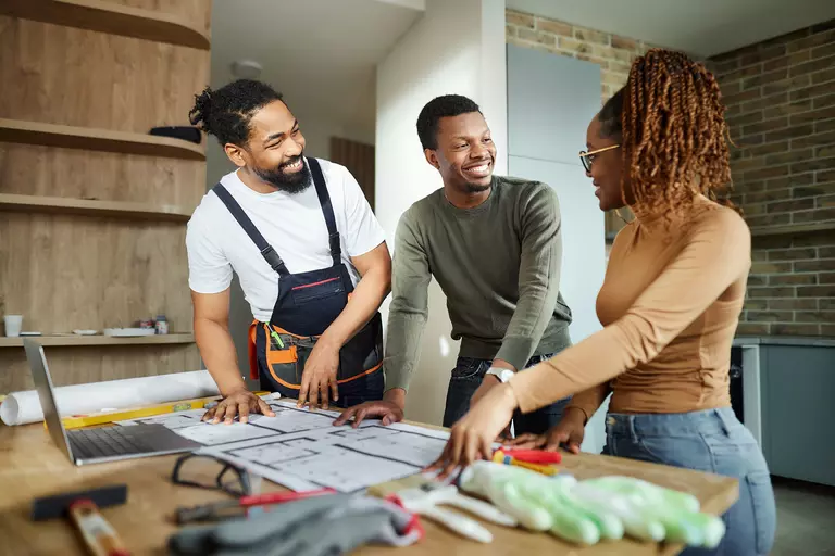Two men and a woman working together to create a home renovation plan.