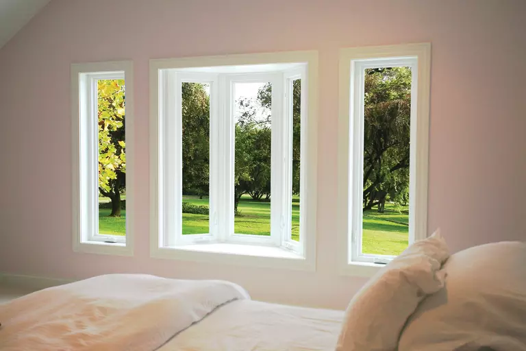 Bay window looking onto a green grassy field with trees.