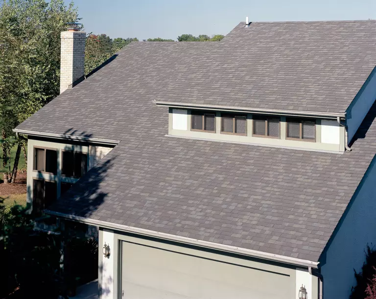 Home roof with asphalt shingles using a mix of brown, blue-gray, and dark gray granules.