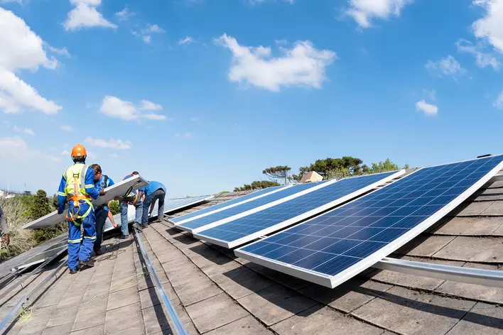 Professionals installing solar panels onto the roof of a home to increase overall energy efficiency and save money on electricity.