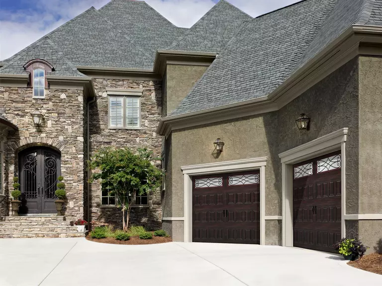 Home with a stone veneer and stucco exterior featuring gray windows.