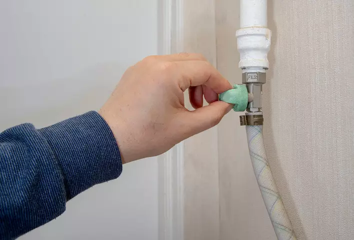 Man's hand to open and close the gas valve of a water heater.