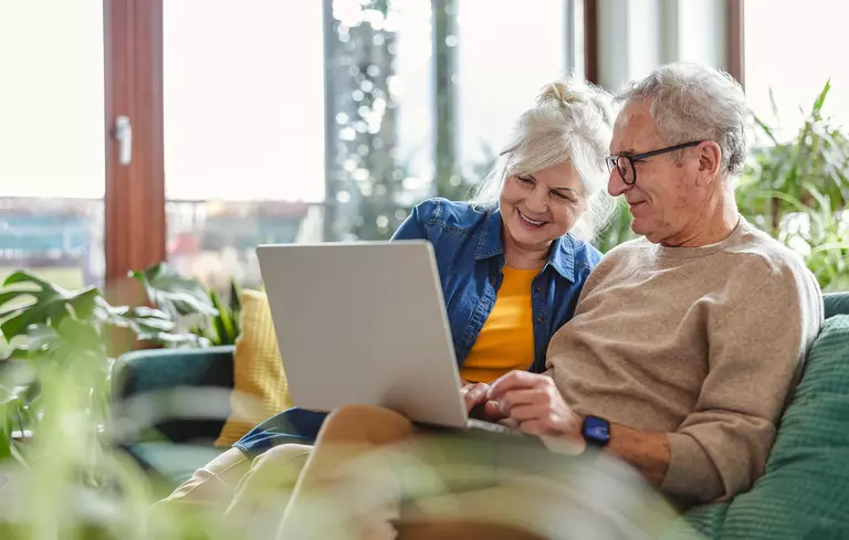 Couple researching on a computer on a couch.